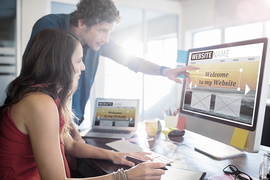 A man and woman looking at the computer monitor